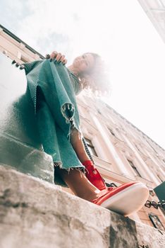 Woman in a red stylish suede loafer shoes, blue jeanse, white shirt and trendy checkered coat. Pair of trendy female loafers shoes, outdoors