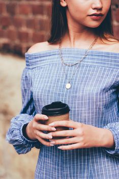 A female in a striped jumpsuit posing with a coffe cup. summertime