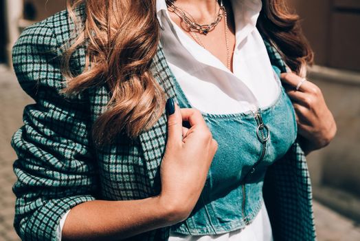 Fashionable young woman with blond hair dressed in white blouse and denim top so checkered coat posing. Street style.