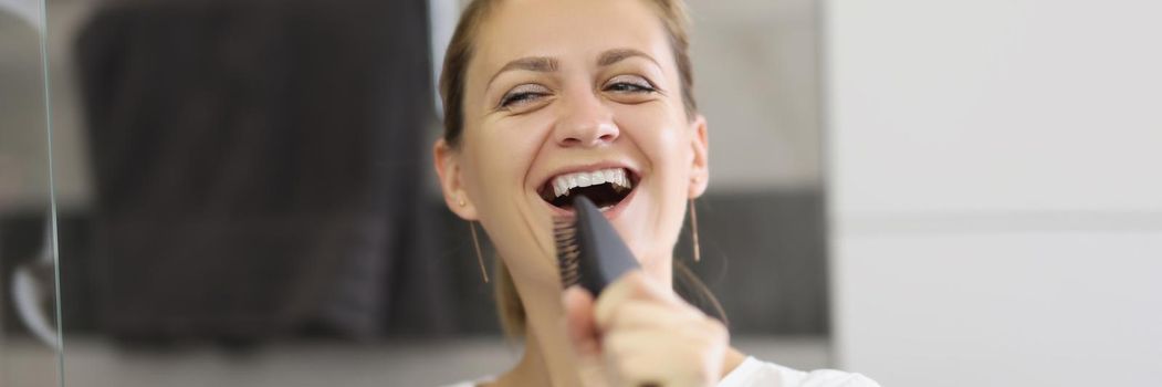 Portrait of cheerful brunette woman sings using brush as microphone, perform concert in bathroom, start day in good mood, positive attitude. Good morning, positivity, get ready, wellness concept