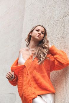 Portrait of fashionable blond women in orange sweater and beige sweater posing in the street