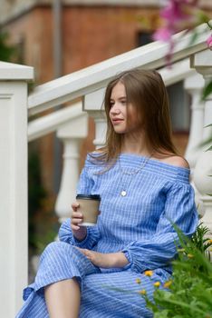 A female posing near flower on a stone curb wearing a striped jumpsuit. summertime