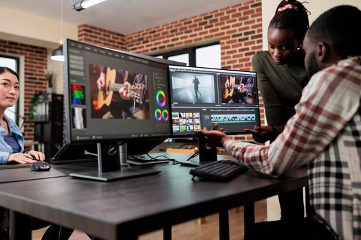 African american professional video editors enhancing digital footage using specialized software. Expert videographers in office workspace editing and improving frames on workstation.