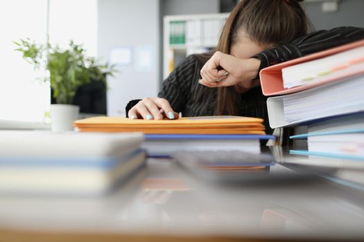 Close-up of tired overworked woman sleeping on workplace. Stressful and exhausted clerk in office, lots of stack with documents on desk. Hardworker, businesswoman, job concept