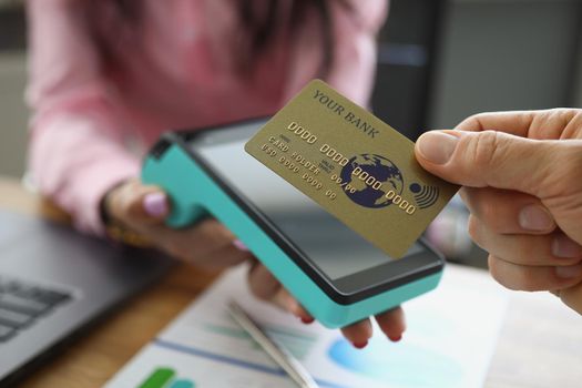 Close-up of customer holding credit card near nfc technology on counter, contactless payment for bill at store or cafe. Modern technology, transaction, cashier machine concept