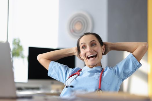 Portrait of laughing medical worker on break, doctor watch video on laptop, free time, qualified female in office. Medicine, healthcare, clinic, lunch, spare time, fun concept