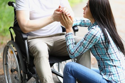 Portrait of young woman comforting man in wheelchair, assure him in sooner recovery. Female hold husband hand. Healthcare, accident, injury, family, relationship, support concept