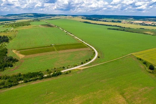 Amazing wide aerial view from drone of big road curve, countryside, fields, and cloudy sky