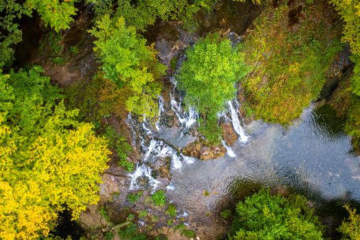 Top view from drone of beauty waterfall between trees in autumn