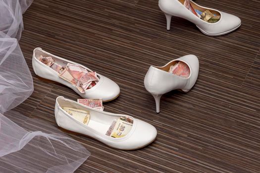 a white wedding shoes full of money and currency. ritual at some weddings-the shoe is filled with money then the bride is given to the groom.