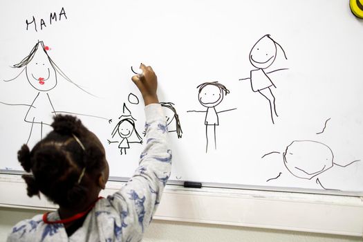 Moscow, Russia - 15 March 2022, A five-year-old girl draws a family on the blackboard. Charitable Center for Support and Adaptation of Refugee and Migrant Children "The Same Children"