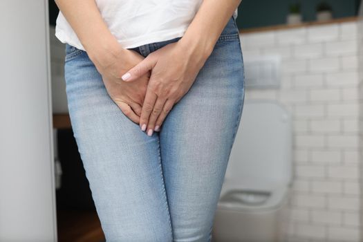 Close-up of woman with natural need to pee, incontinence, nature call. Female close lower body with hands, cant stand. Bathroom, toilet, hygiene, restroom, wc concept. Blurred background