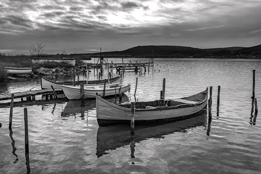 The tranquil afternoon on a lake with a wooden pier and boats.