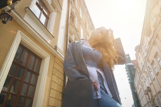 Woman in a blue jeanse, white shirt and trendy checkered coat posing on the street. Street photo