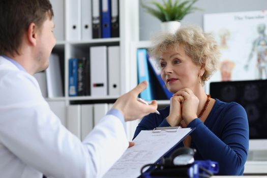 Portrait of senior female on doctors appointment in clinic. Qualified doctor explains woman therapy for recovery, prescription for healing. Healthcare, modern medicine, hospital concept