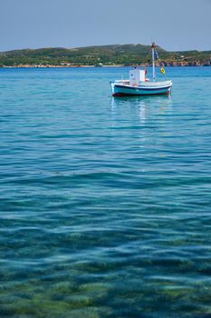 Greek fishing boat moored in blue waters of Aegean sea in harbor of near Milos island, Greece