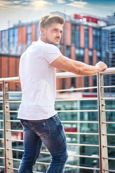 Handsome fit man in white t-shirt outdoor in city setting, looking away