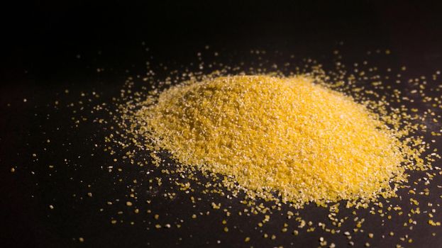 Raw corn grits flour on black background