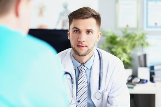 Portrait of young male doctor in uniform and stethoscope, work meeting in head doctor office. Listen to instructions of professional specialist, plan for work. Hospital, medicine concept