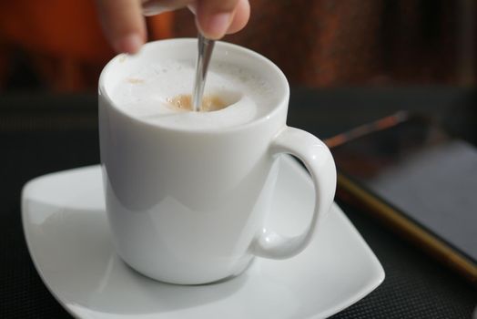 person hand stirring coffee with spoon