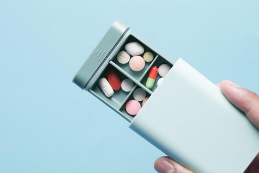 man's hands taking medicine from a pill box .