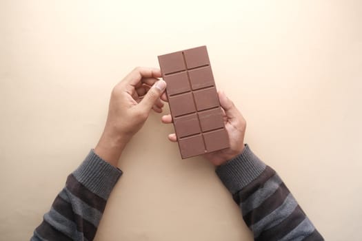 top view of holding dark chocolate on orange background .