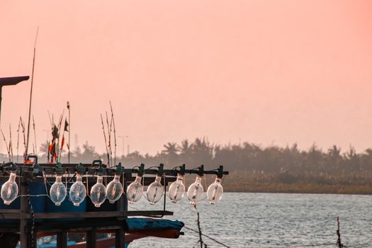Lights on a fishing boat against the pink sunset sky in Koh Sdach Island in Cambodia