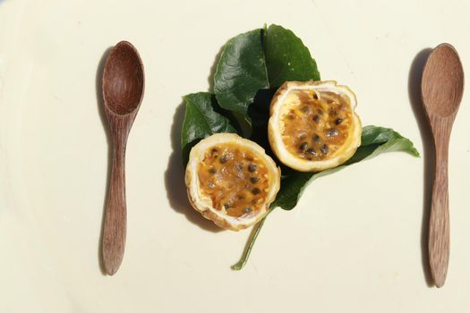 Top view of wooden spoon and yellow passion fruit sliced in half
