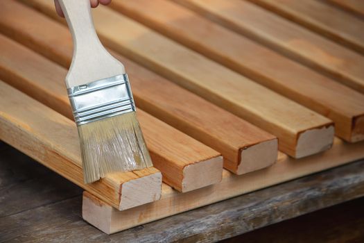 Painting wooden furniture with varnish. a man hides a tree with varnish. Selective focus