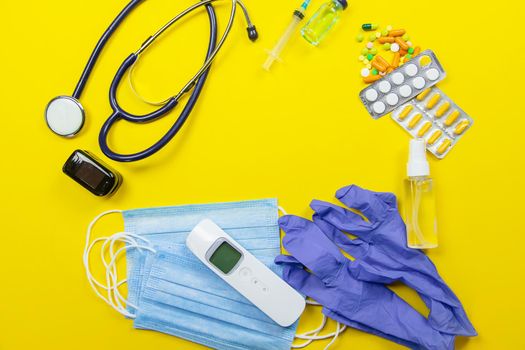 medical supplies on a yellow background, pills water treatment mask virus.