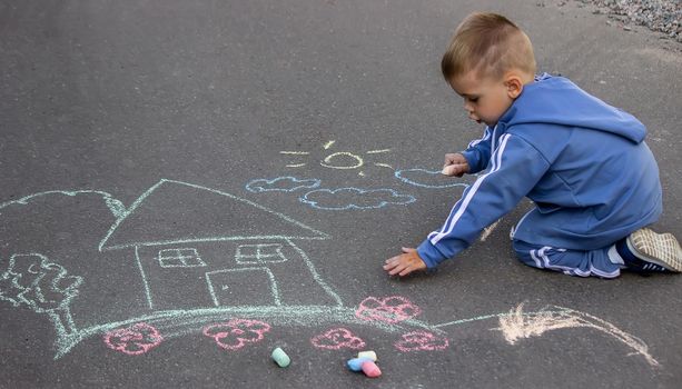 children drawing on asphalt family house. Selective focus