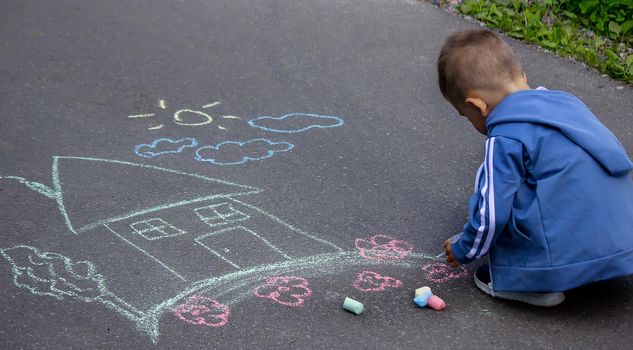 children drawing on asphalt family house. Selective focus
