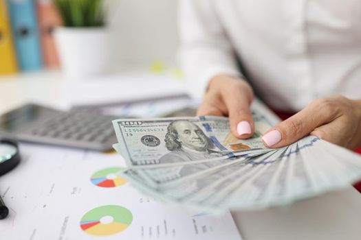 Close-up of female manager calculates company finances counting banknotes, money for investment, corporate profit. Business, bank, finance, economy, accounting, cash concept. Blurred background