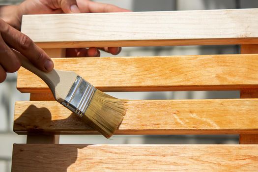 Painting wooden furniture with varnish. a man hides a tree with varnish. Selective focus