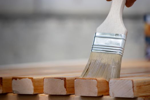 Painting wooden furniture with varnish. a man hides a tree with varnish. Selective focus