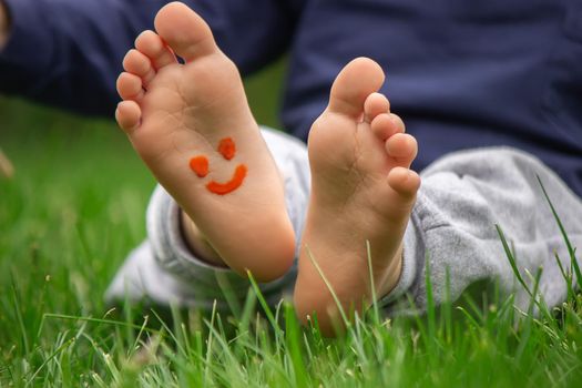 child sitting on the grass, smiling on the child's leg with paints