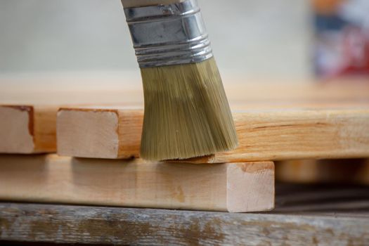 Painting wooden furniture with varnish. a man hides a tree with varnish. Selective focus