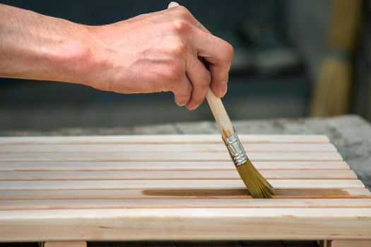 Painting wooden furniture with varnish. a man hides a tree with varnish. Selective focus