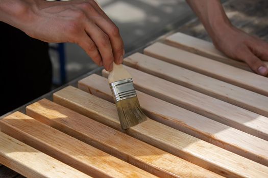 Painting wooden furniture with varnish. a man hides a tree with varnish. Selective focus
