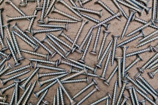 A lot of silver metal screws on the table close-up, background.
