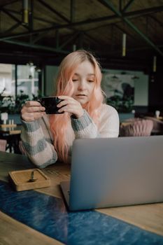 Pretty female student with cute smile keyboarding something on net-book while relaxing after lectures in University, beautiful happy woman working on laptop computer during coffee break in cafe bar