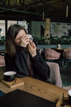 Lesbian couple taking photo of each other on a camera in cafe. art