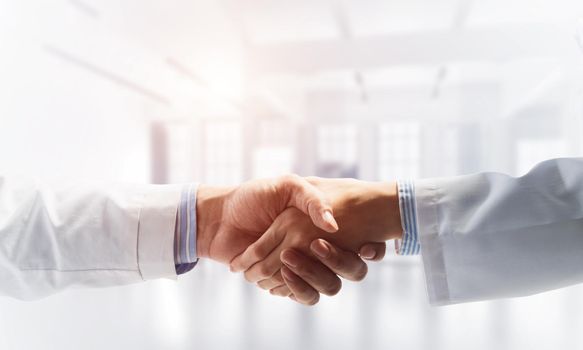 Close-up of the handshake between the two medics. Against the backdrop of the office