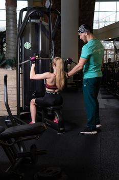 RUSSIA, MOSCOW - FEB 11, 2022: A girl is engaged in a led press simulator in a red blonde beautiful on a black background leg gym training man flexing, for healthy strength in fitness from exercise club, power male. Woman female sportswear, sporty trainer