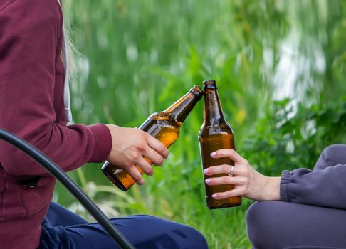 The hand of a man holding a beer bottle in nature. rest by the river. Nature. Selective focus