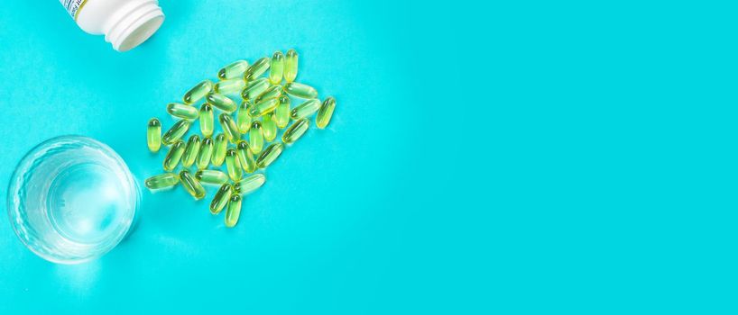 Omega 3 fish oil capsules spilling out of a bottle on a blue background.