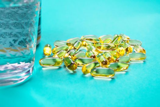 Omega 3 fish oil capsules spilling out of a bottle on a blue background.