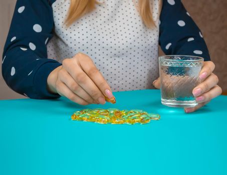 Omega 3 fish oil capsules spilling out of a bottle on a blue background.