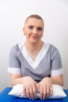 Smiling female doctor cosmetologist in lab coat looking at camera over light background.