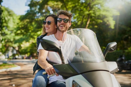 Cropped shot of a young attractive couple riding a scooter around town.